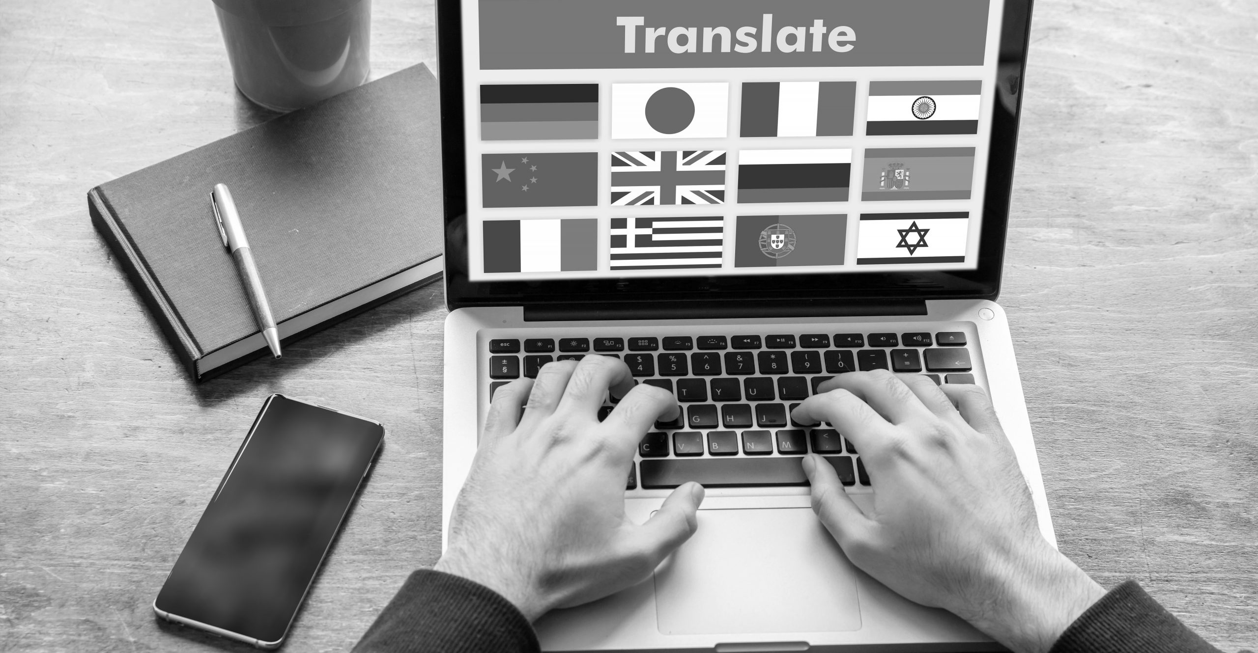 Illustrasjonsfoto: Arbeid på flere språl. Mann som jobber fra en pc som viser forskjellige flagg og teksten "Translate".
