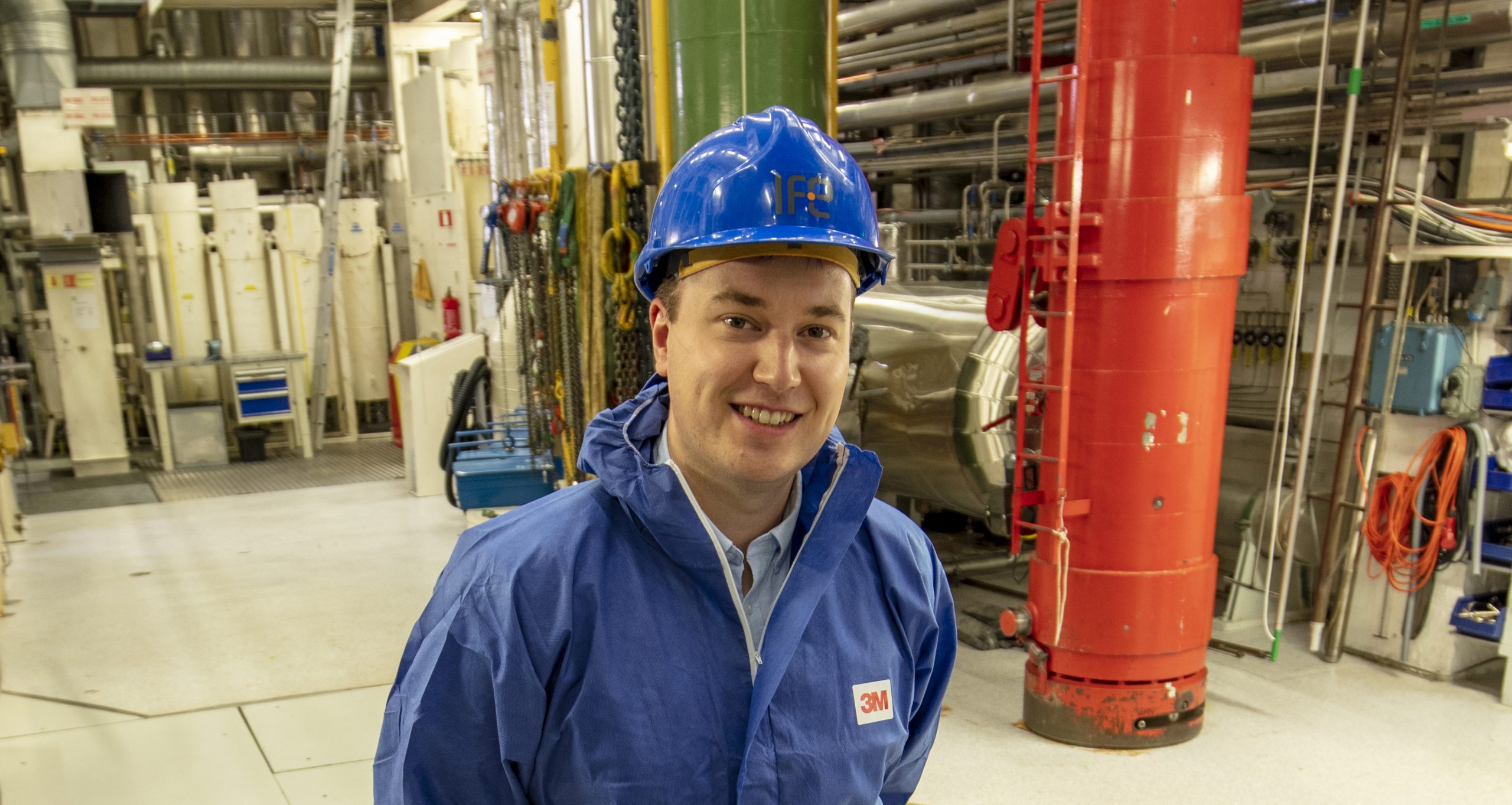 Bilde av Håvard Kristiansen, iført blå vernedress og blå hjelm. På besøk i atomreaktor.