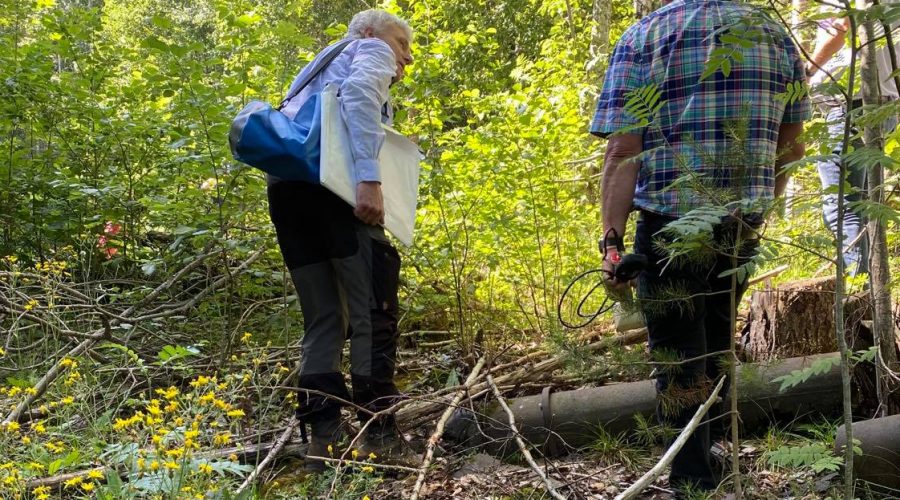 Bilde av to sivilt kledde personer på befaring i området rundt Søve gruver (skog).