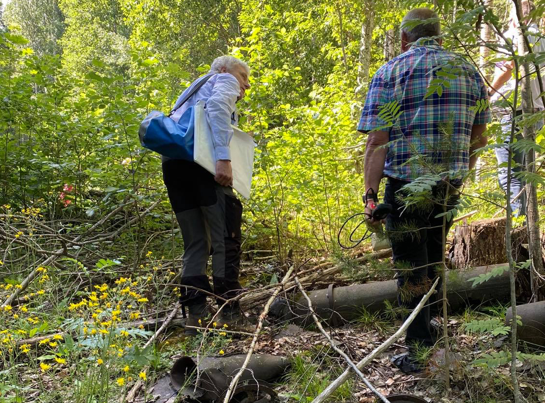 Bilde av to sivilt kledde personer på befaring i området rundt Søve gruver (skog).