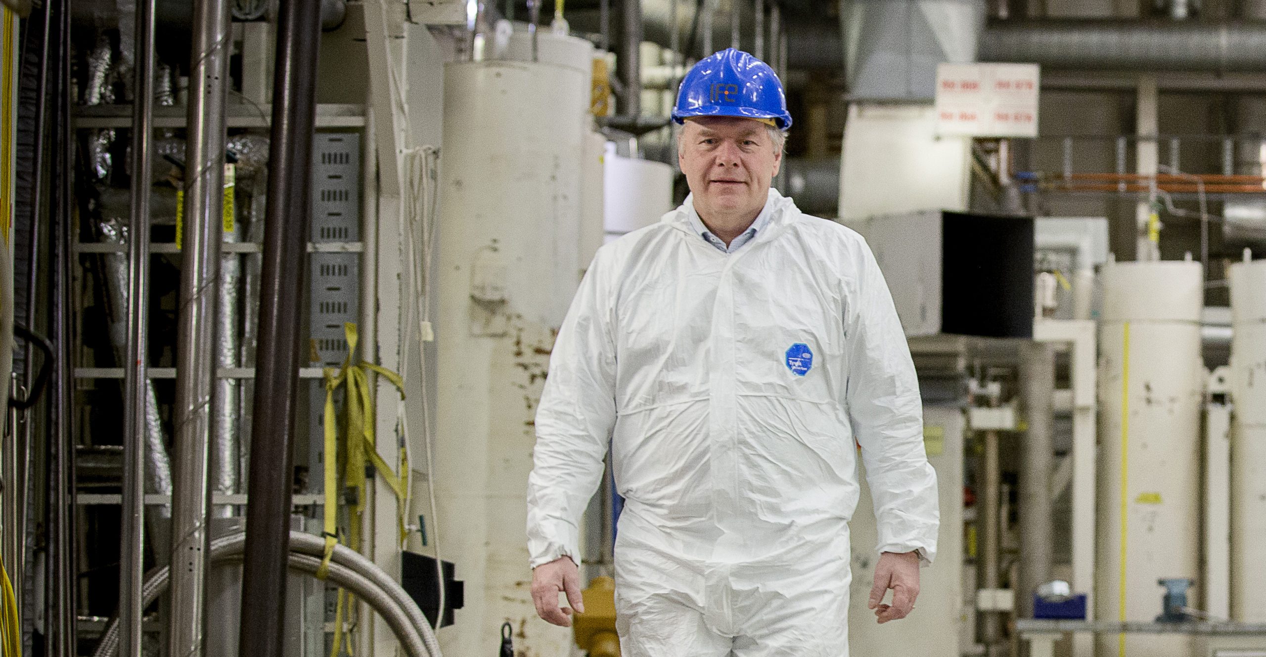 Bilde av NNDs direktør Pål Mikkelsen, på besøk i atomreaktoren i Halden. Iført hvit vernedress og blå hjelm.